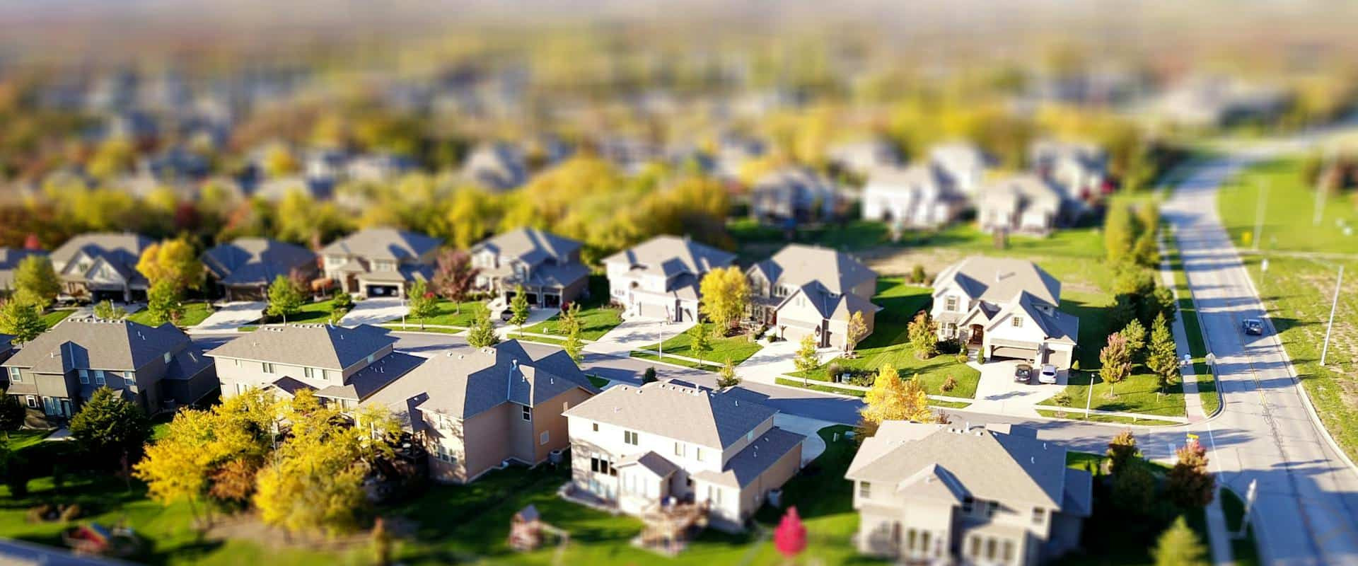 Tilt-Shift Aerial Photo Of A Suburban Neighborhood With Green Lawns And Roads. Tilt-Shift Aerial Photo Of A Suburban Neighborhood With Green Lawns And Roads.